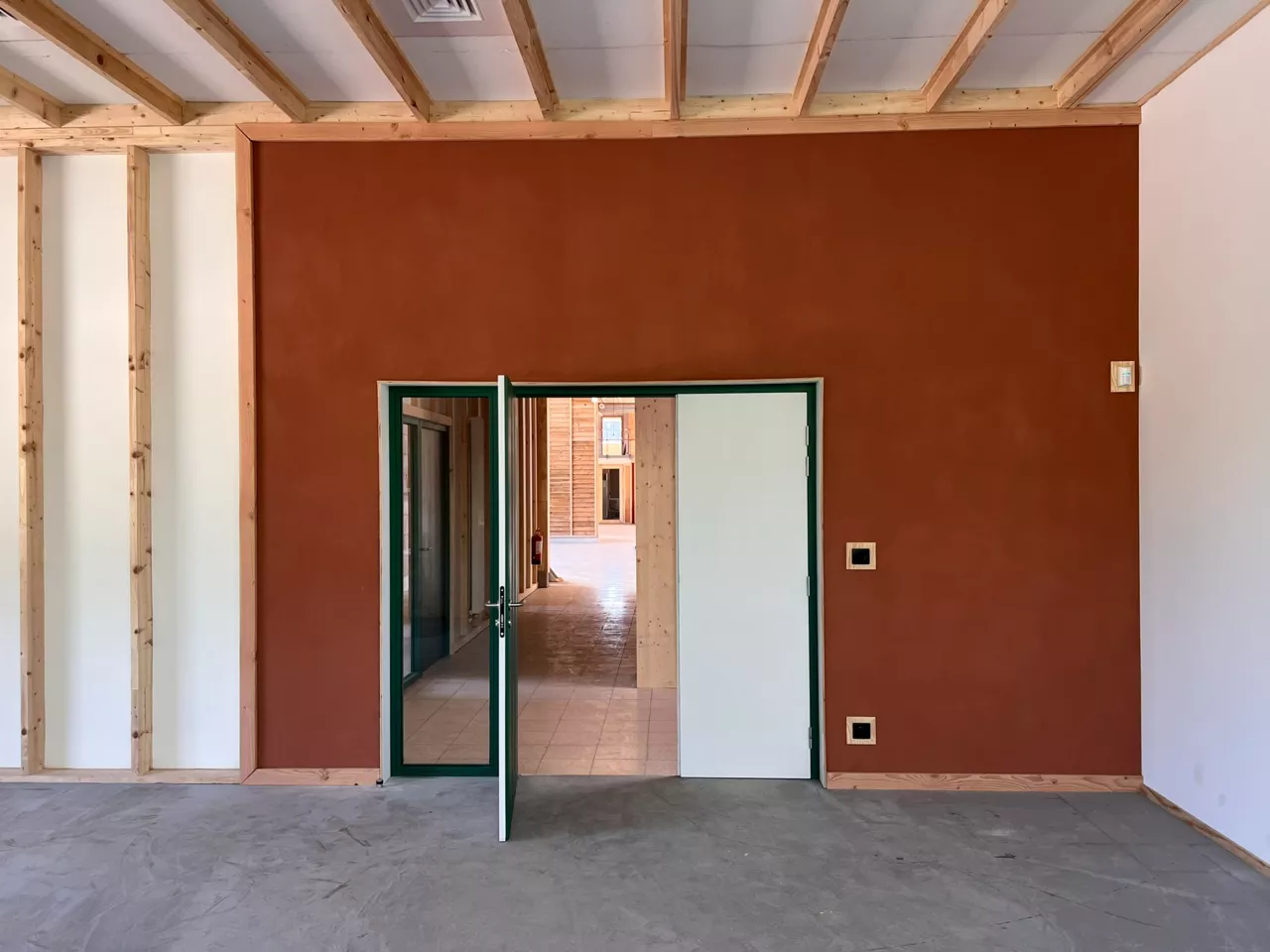 Mur enduit de terre crue rouge intégrant un système de chauffage mural à eau chaude, dans le bâtiment démonstrateur de Noeux-environnement. Une solution biosourcée innovante qui associe esthétique naturelle et confort thermique durable.